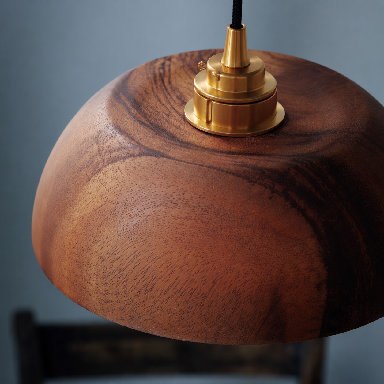 Close-up of brass-tone holder on walnut dome pendant