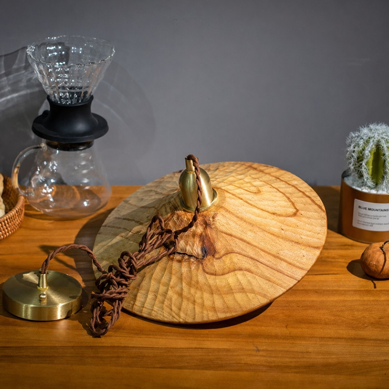 Brass-toned cap and cord detail on wooden pendant light